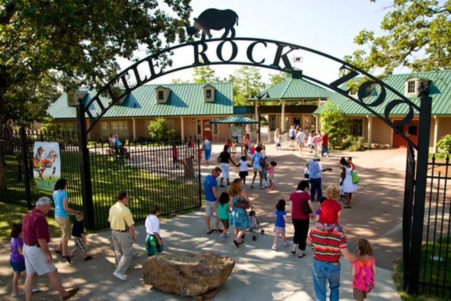 Visitors walking under the Little Rock Zoo entrance arch on a sunny day